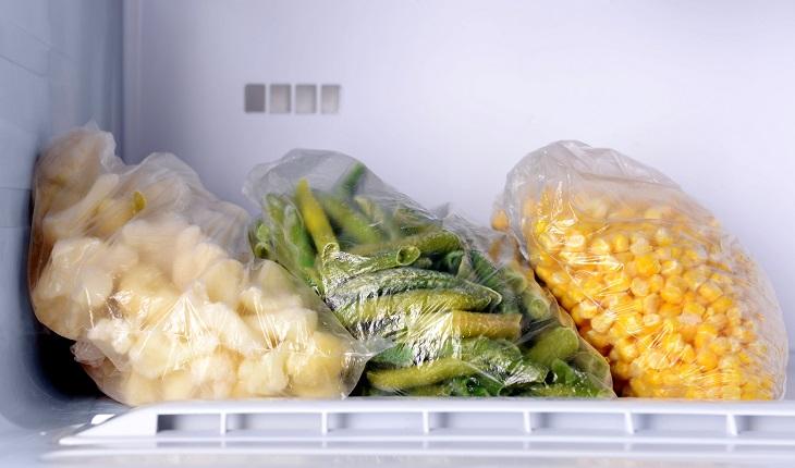 Sacos de vegetais congelados e grãos de milho dentro do freezer.
