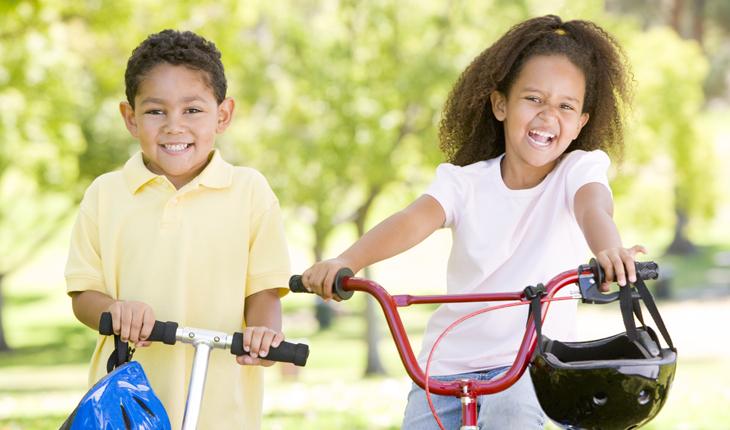 uma imagem com crianças sorrindo e andando de bicicleta e patinete