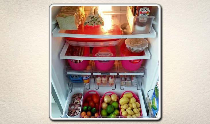 Na imagem é possível ver uma geladeira que está toda organizada por cestos rosas para separar os tipos de alimentos.