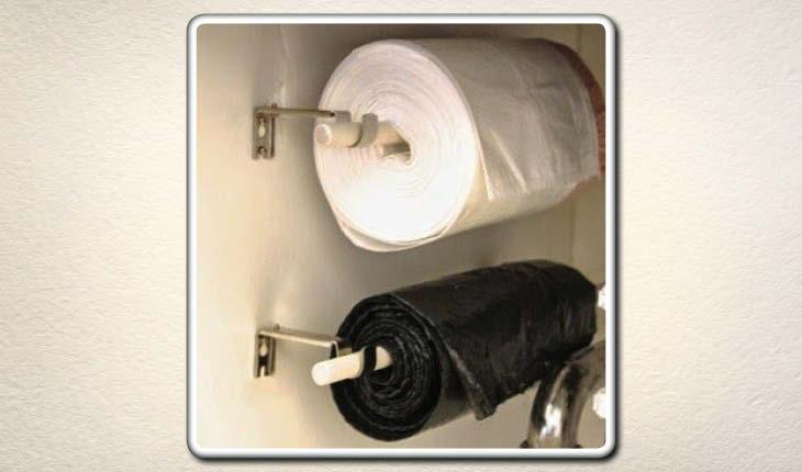 Na imagem há dois suportes de papel toalha que estão colocados dentro de um armário. Em um deles há papel toalha e no outro um rolo de sacos de lixo.