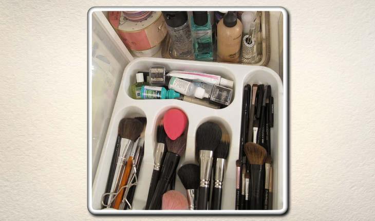 Na imagem, um recipiente próprio para talheres está sendo utilizado para organizar itens de maquiagem.