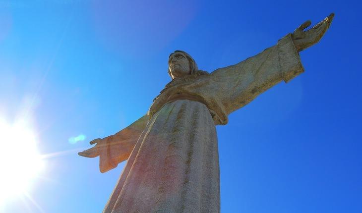 Estátua de Jesus Cristo de braços abertos vista de baixo para cima. Envelhecimento saudável