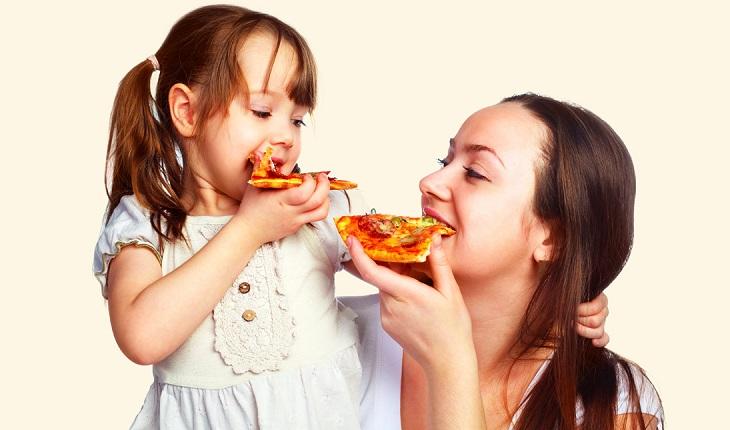 mãe e filha comendo pedaços de pizza