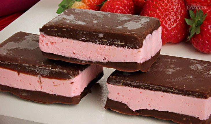 receita de bombom de sorvete, o recheio é cor-de-rosa e a cobertura é de chocolate ao leite.
