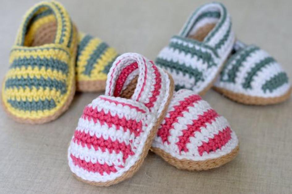 Na imagem há um modelo como ideia para fazer sapatinhos de crochê feito em três cores diferentes. O que está mais a frente é rosa e branco, outro é amarelo e verde e o outro é azul e branco.