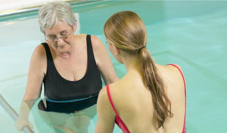 Mulher idosa com professora na piscina