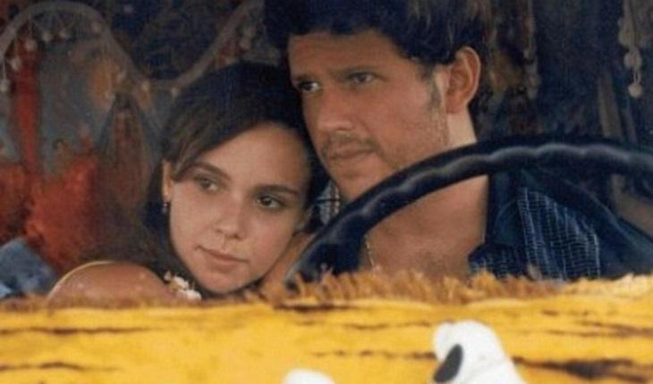 Casal abraçado em banco de carro amarelo em cena de filme brasileiro romântico