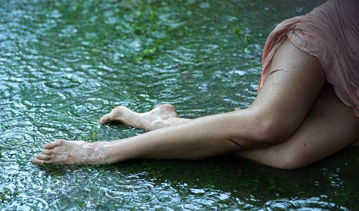 Na imagem, a perna da mulher está deitada no chão molhado. Consulta ginecológica.