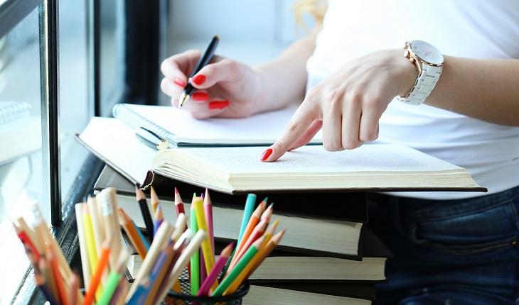 Na foto há uma mulher folheando um livro com um lápis na mão. Organizar suas atividades do dia ajuda você a ser mais focada e produtiva