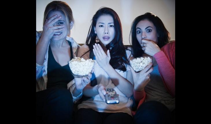 Mulheres vendo televisão e comendo pipoca