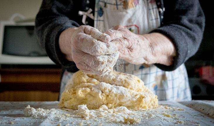mãos de mulher idosa sovando pão