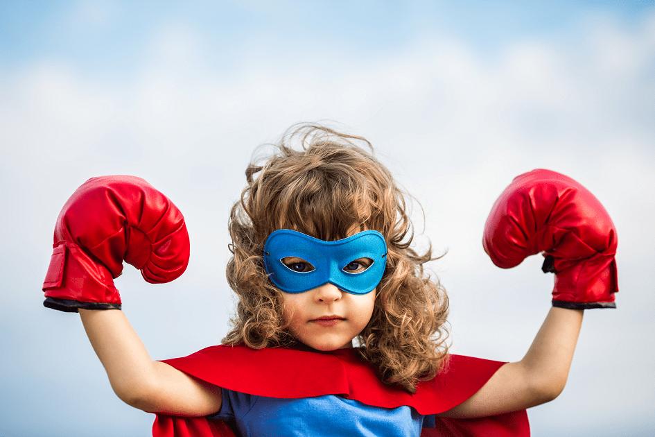 Menina usando máscara azul, capa vermelha e luvas de boxe vermelha para ilustrar o tema 5 motivos para ensinar inglês para crianças com autismo 