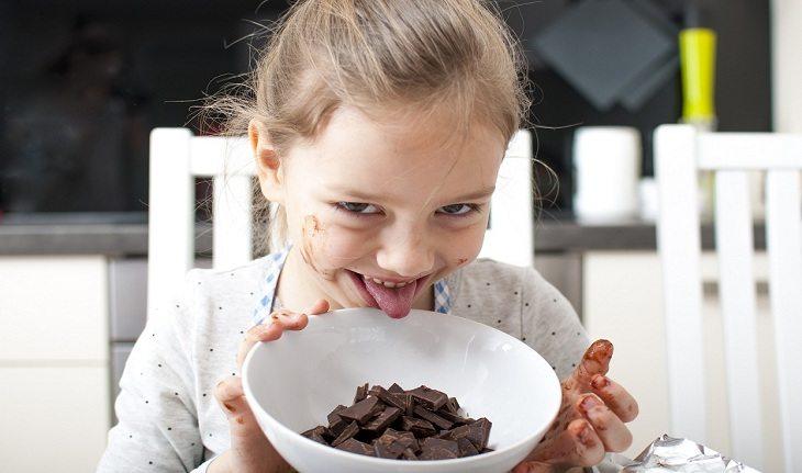 Imagem de uma menina comendo chocolate em um pote - Ana Júlia