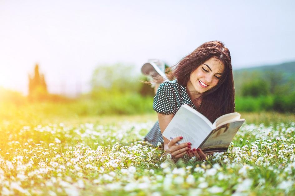 imagem de uma mulher feliz, leve e lendo um livro