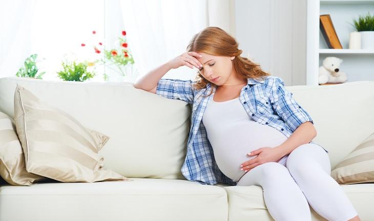 Gravidez: imagem de uma mulher grávida sentada em um sofá demonstrando preocupação.
