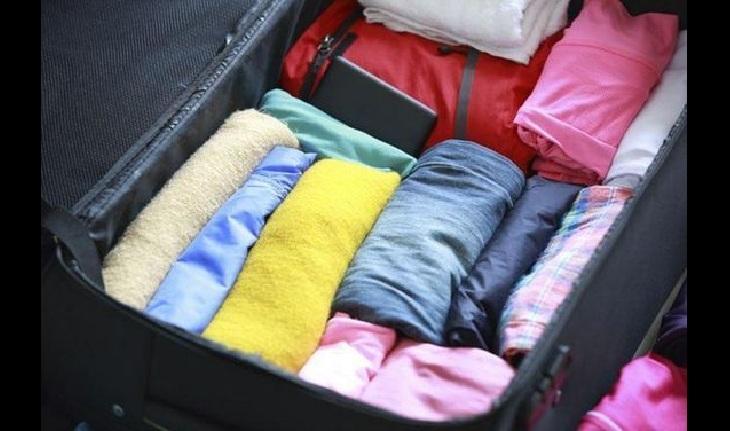 imagem de uma mala aberta com roupas embrulhadas em forma de rolinhos - truques de viagem