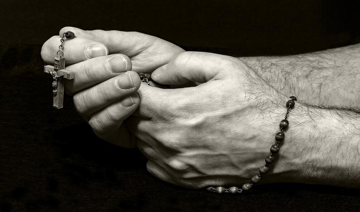 Imagem de uma pessoa com um terço nas mãos orando. Amor protegido