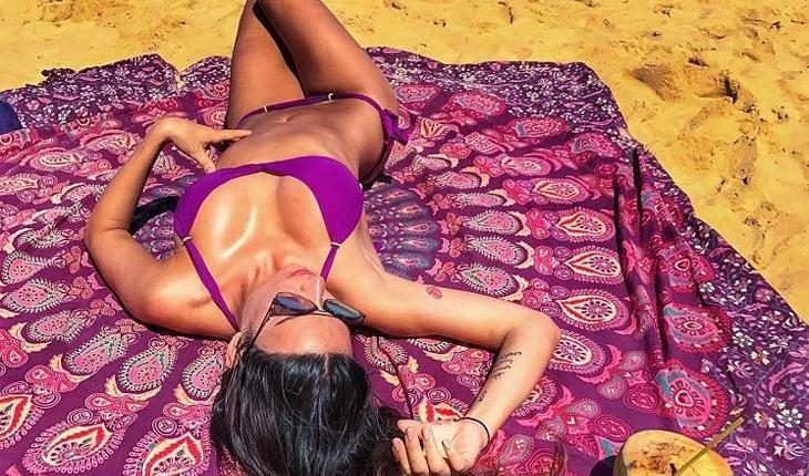 atriz Thaila Ayala deitada em uma canga com biquini, na praia