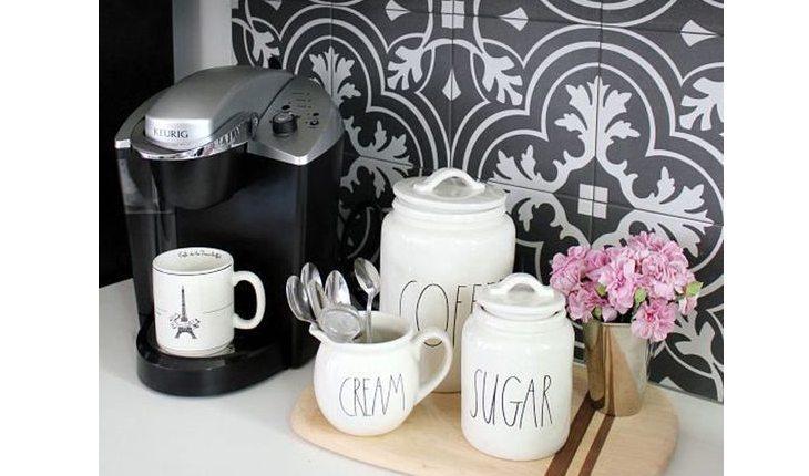 cantinho do café com potinhos de açúcar, colheres e café ao lado da cafeteira