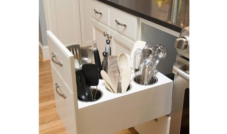 A foto mostra uma gaveta grande com espaços par aguardar utensílios como colheres e batedores.