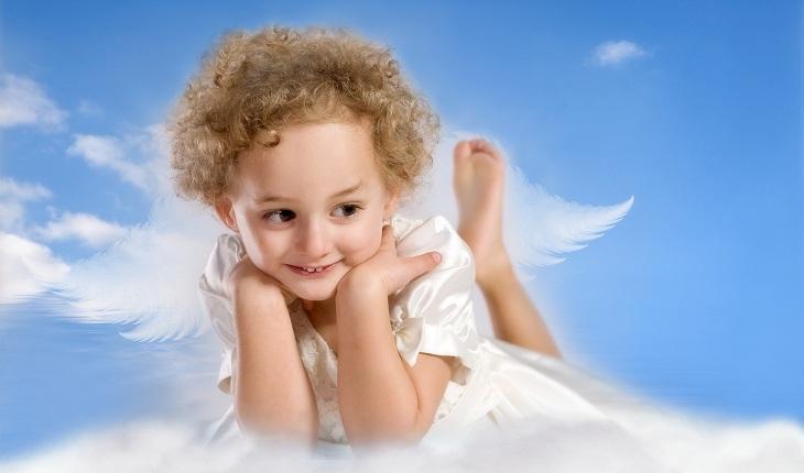criança vestida de anjo em cima de nuvem com céu azul atrás