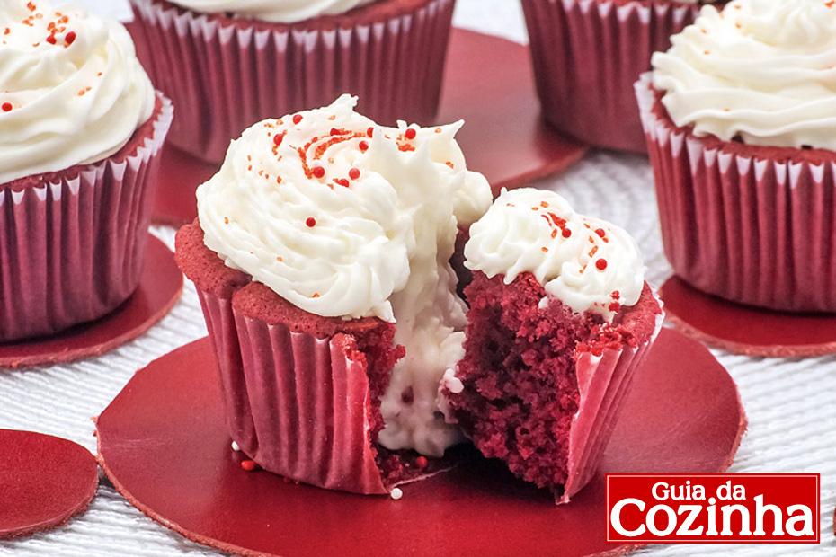 cupcake red velvet com bastante recheio branco escorrendo.
