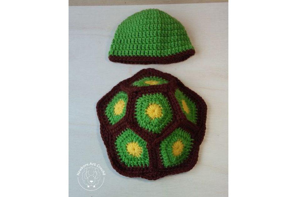 Na foto há uma fantasia de uma tartaruga feita de crochê. Os tons são verdes e marrons.