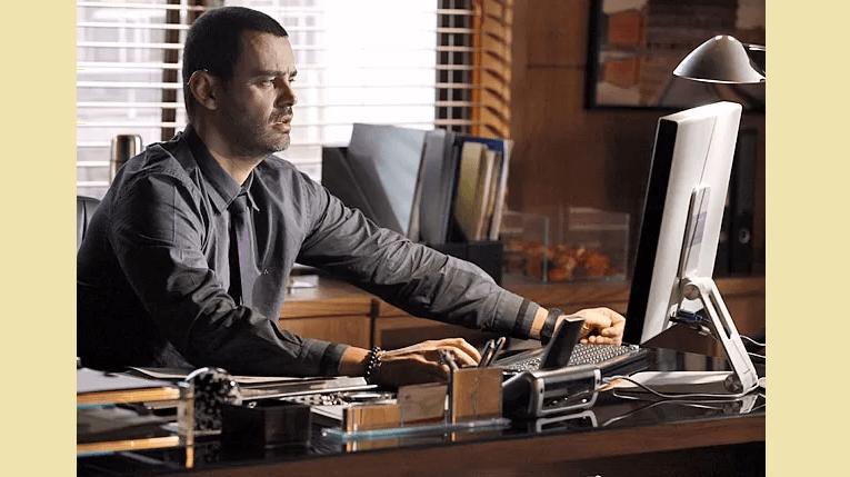 Na foto, o personagem de Carmo Dalla Vecchia está em um escritório, mexendo em um computador. Invejosos das novelas