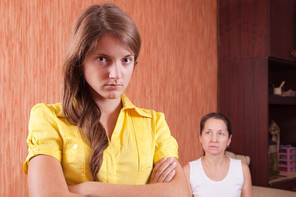 Adolescente brava de blusa amarela virada de costas para sua mãe sentada no sofá