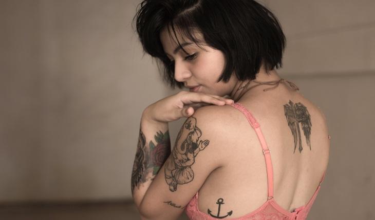 mulher de blusa rosa com tatuagens no braço