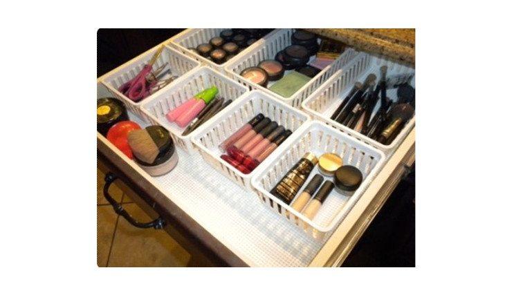 Na foto há uma gaveta com diversas cestinhas de plástico decoradas dentro que servem como divisórias que organizam maquiagens.