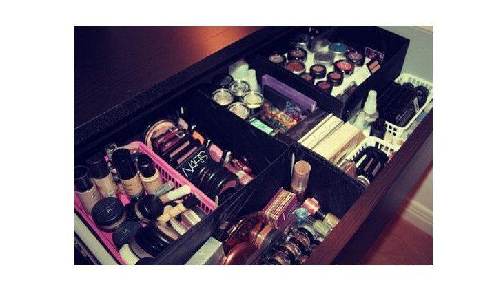 Na foto há uma gaveta em que caixas de sapato são as divisórias que organizam maquiagens. As caixas estão encapadas de preto.