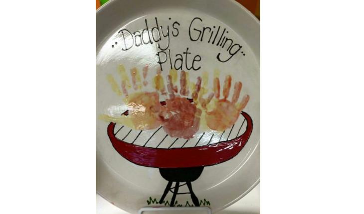 Na foto há um prato decorado com as mãos de crianças carimbadas dentro com a cor laranja.