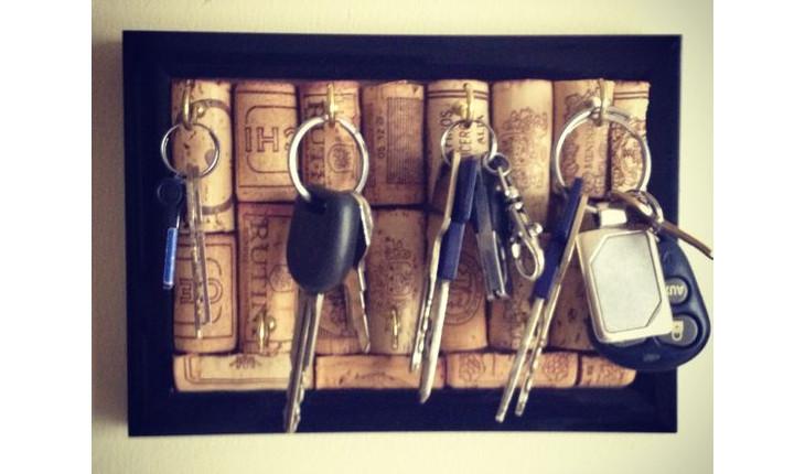 Na foto há um porta-chaves feito com uma moldura de madeira e rolhas. Há chaves penduradas.