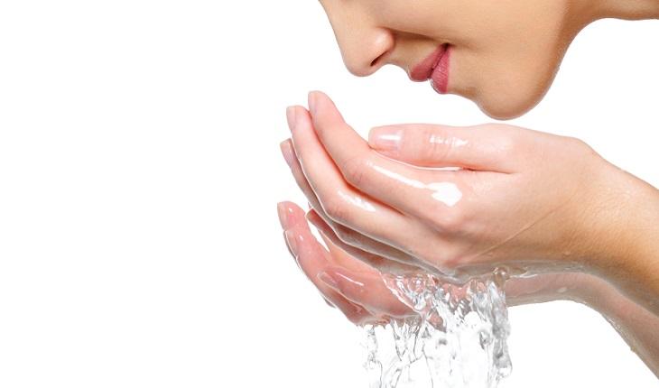 mulher lavando o rosto com água