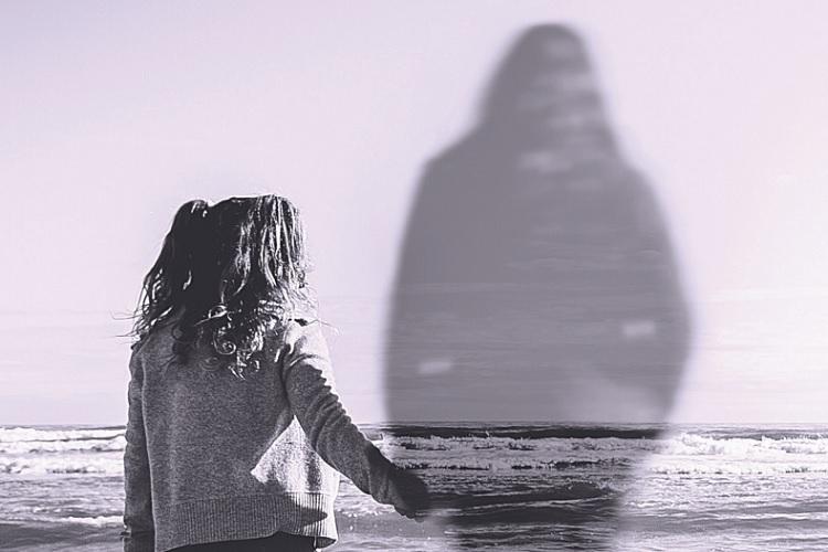 A foto mostra uma menina segurando a mão de um espírito na beira da praia.Tipos de obsessões