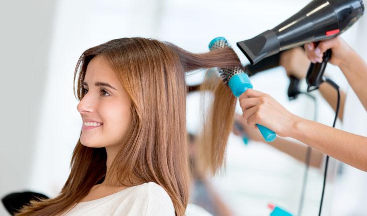 cabeleireiro fazendo escova no cabelo de uma cliente