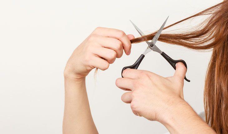mulher cortando uma mecha do cabelo