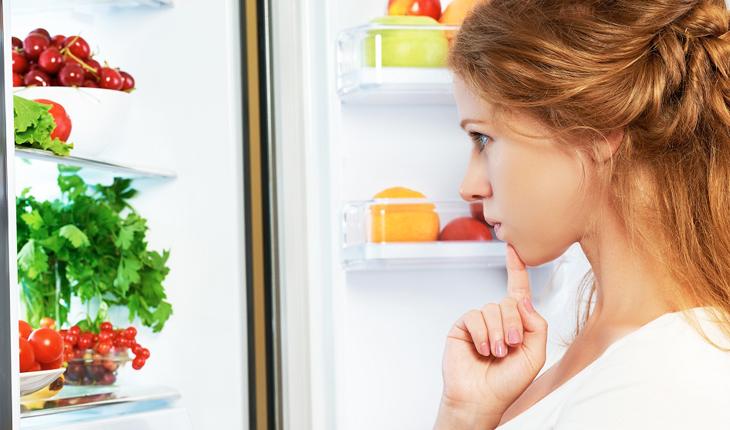 mulher olhando a geladeira
