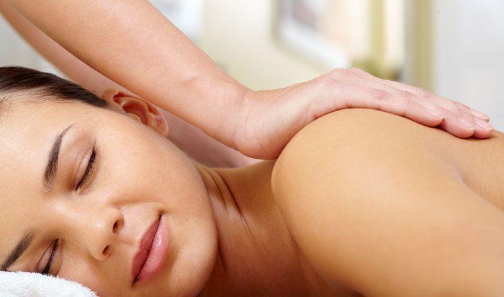 mulher deitada de bruços recebendo massagem nos ombros