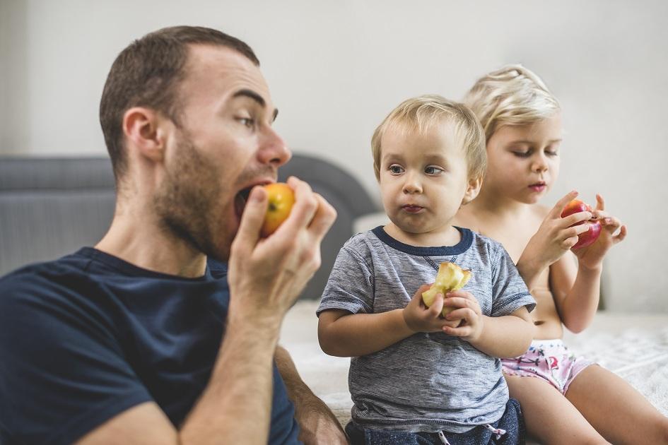 Pai comendo maçã junto com os filhos