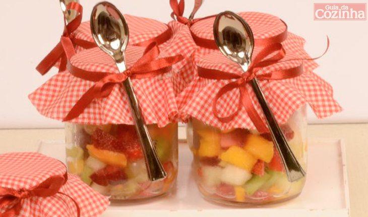 Foto com a receita de salada de frutas no potinho, decorada com tampas personalizaras e colheres em formato galeria