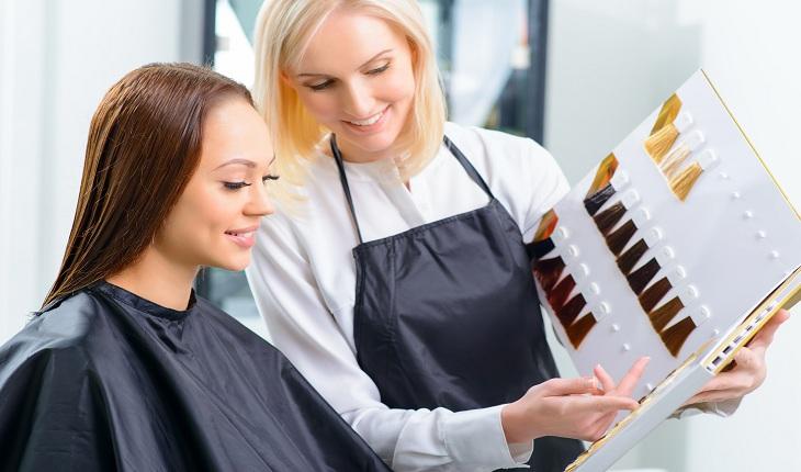 Cabeleireira mostrando uma cartela com vários tons de cor diferente para cabelos à uma cliente que quer colorir o cabelo