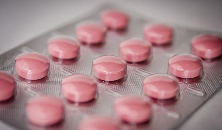Na imagem, uma cartela de pílulas rosa está em foco e bem próximo. Anticoncepcional oral.