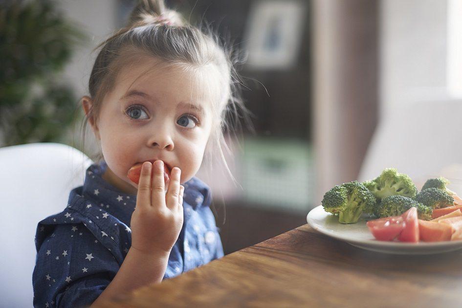 criança sentada comendo vegetais