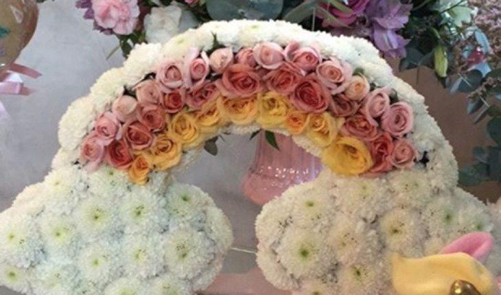 foto do mini arco-íris feito com flores nas cores rosa, branco e amarelo para decorar a mesa do aniversário
