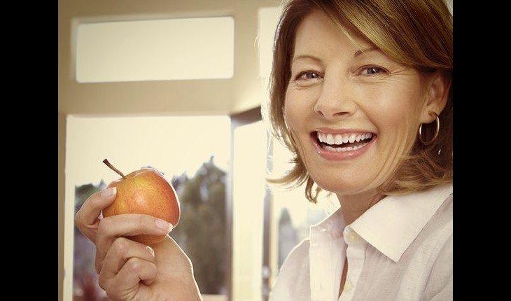 Senhora comendo maçã e sorrindo