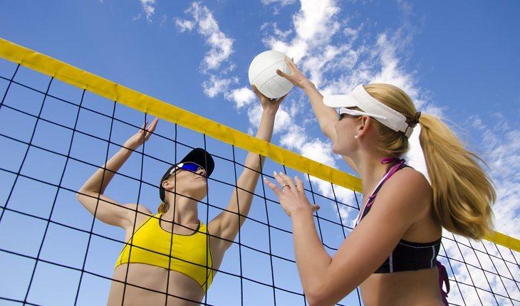 Mulheres disputando bola de vôlei na rede