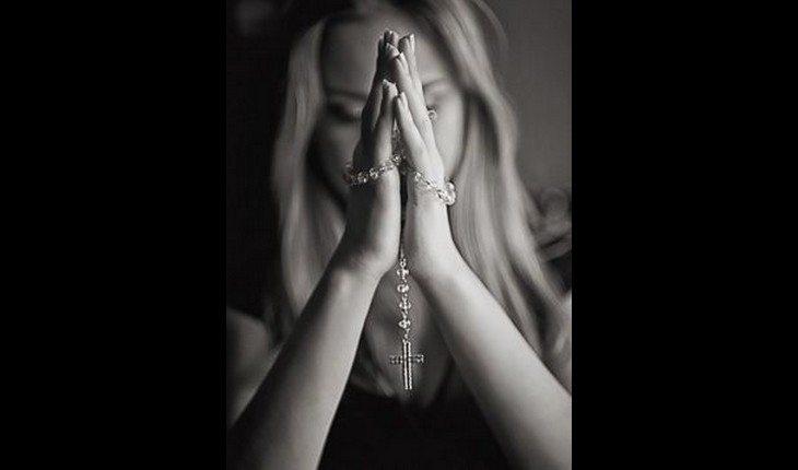 Mulher com as mãos juntas orando