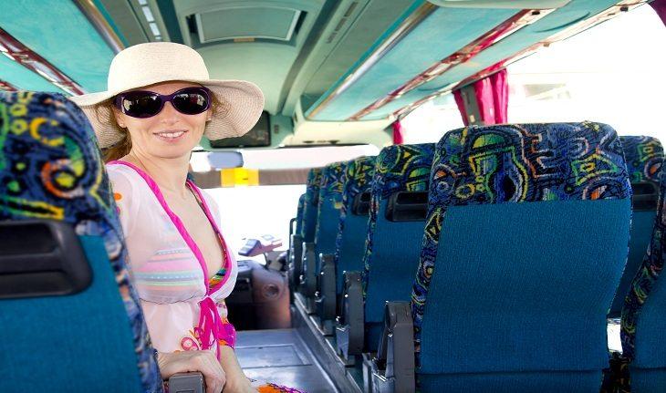 Imagem de uma mulher sentada em um dos assentos de um ônibus.